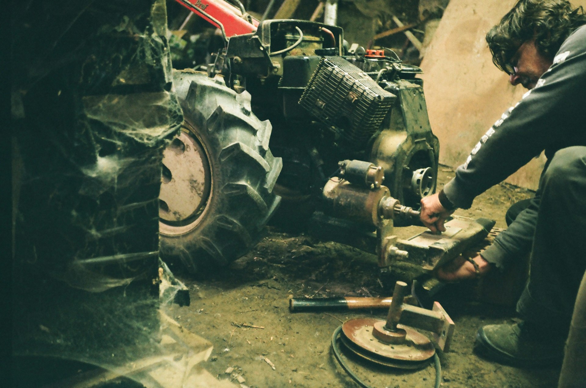 grayscale photo of man in black jacket and pants sitting on tractor